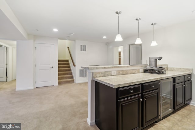 kitchen featuring light carpet, kitchen peninsula, wine cooler, and decorative light fixtures