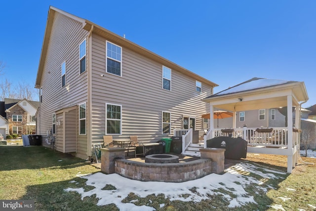 snow covered back of property with a deck and an outdoor fire pit