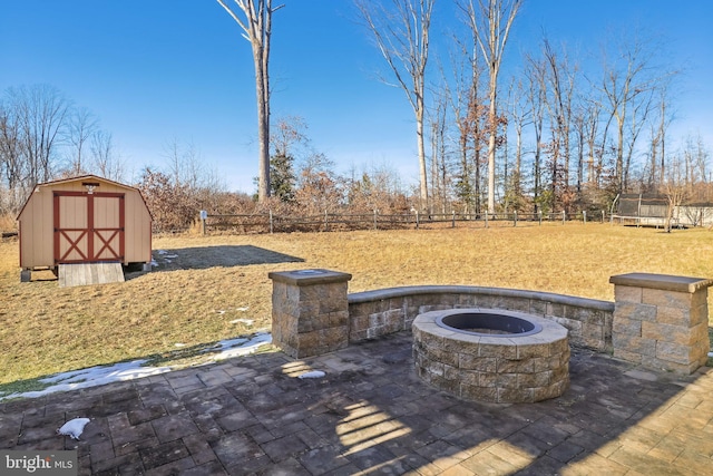 view of patio featuring a trampoline, a storage shed, and a fire pit