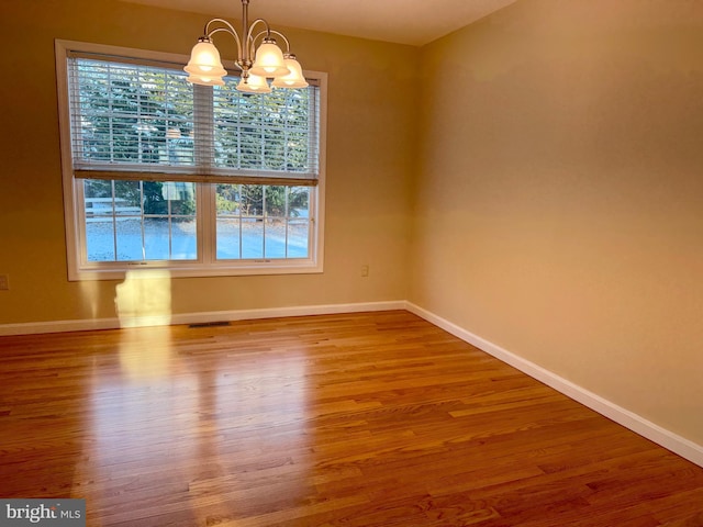 unfurnished room featuring wood-type flooring and a notable chandelier