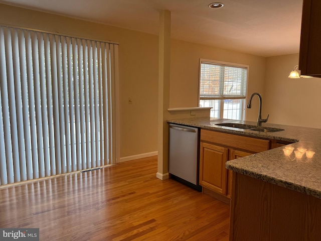 kitchen with hanging light fixtures, sink, stainless steel dishwasher, and light hardwood / wood-style flooring