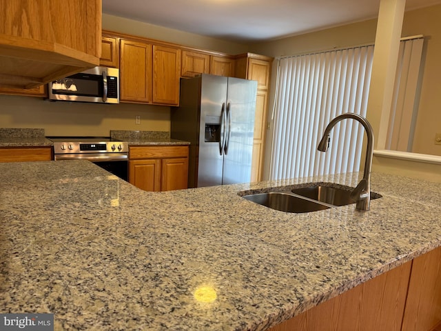 kitchen featuring sink, stainless steel appliances, kitchen peninsula, and light stone countertops