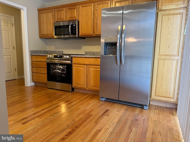 kitchen featuring light stone countertops, light hardwood / wood-style flooring, and stainless steel appliances