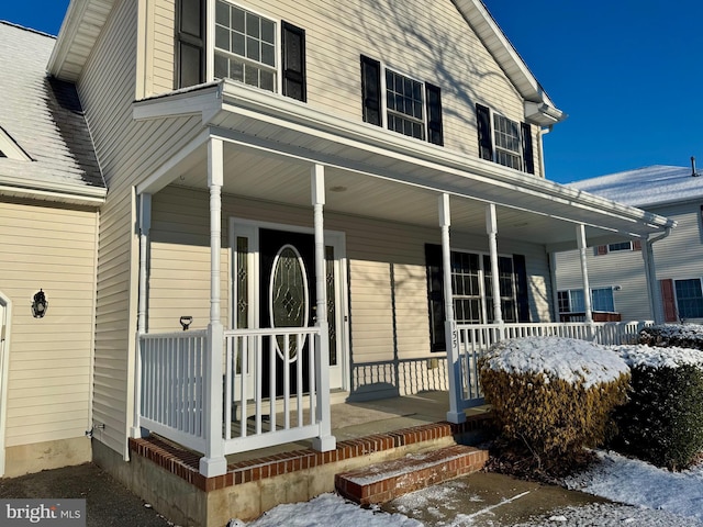 snow covered property entrance with covered porch