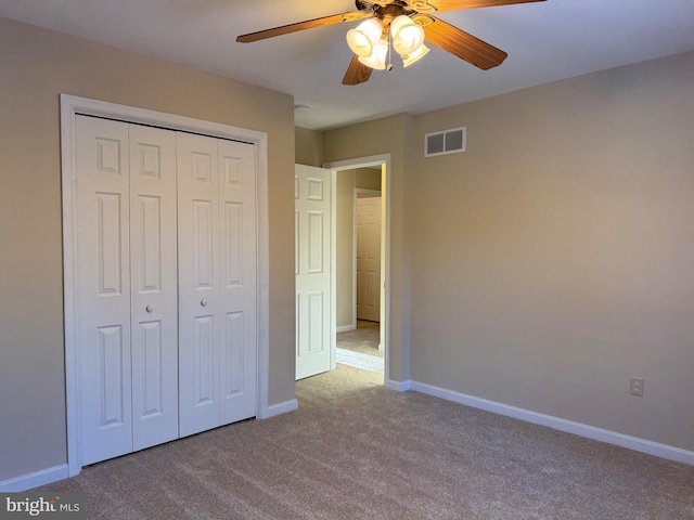 unfurnished bedroom with light colored carpet, a closet, and ceiling fan