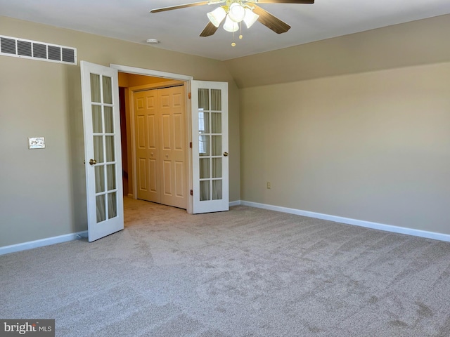 spare room featuring french doors, light colored carpet, lofted ceiling, and ceiling fan