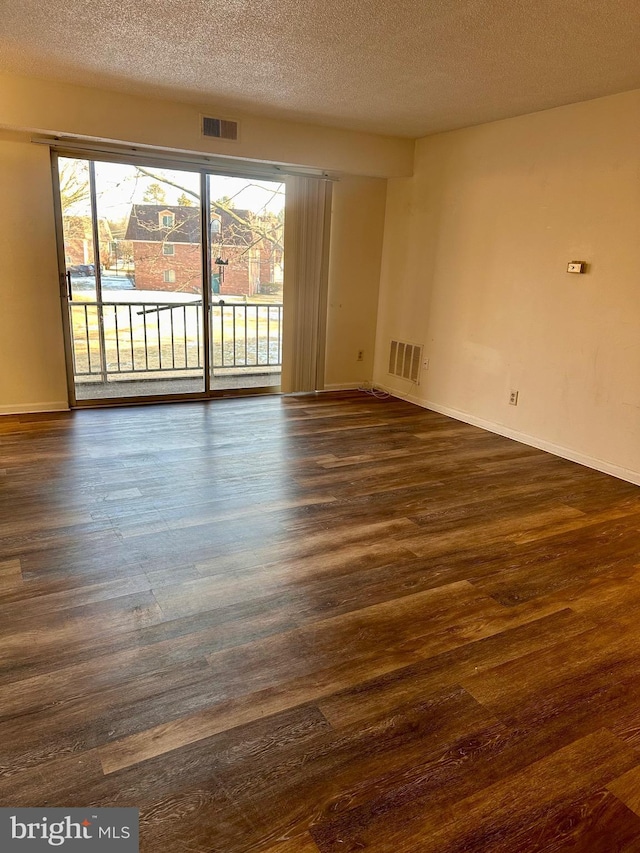 spare room with dark wood-type flooring and a textured ceiling