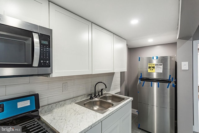 kitchen featuring tasteful backsplash, appliances with stainless steel finishes, sink, and white cabinets