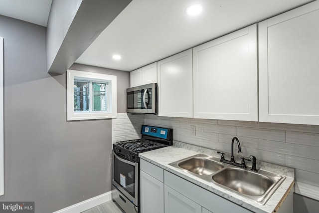 kitchen featuring stainless steel appliances, sink, white cabinets, and decorative backsplash