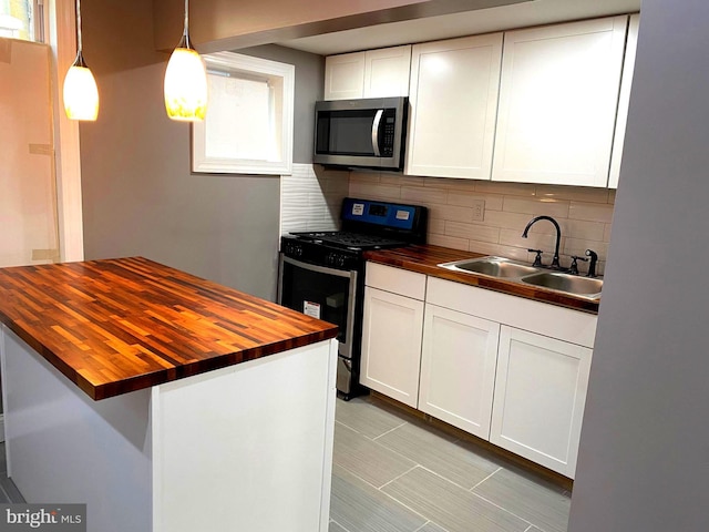 kitchen featuring wood counters, sink, decorative light fixtures, appliances with stainless steel finishes, and white cabinets