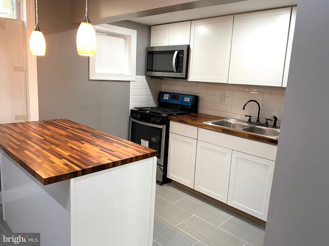 kitchen featuring sink, wooden counters, white cabinetry, stainless steel appliances, and decorative light fixtures