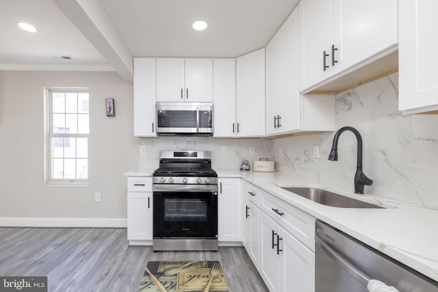 kitchen with white cabinetry, stainless steel appliances, sink, and tasteful backsplash