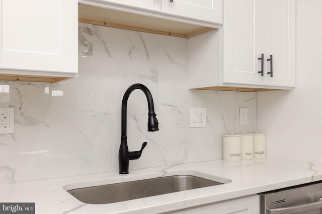 kitchen featuring dishwasher, sink, white cabinets, decorative backsplash, and light stone counters