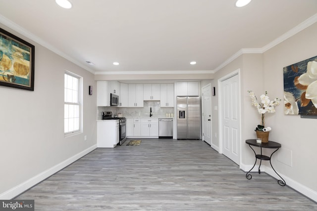 kitchen with crown molding, appliances with stainless steel finishes, white cabinetry, tasteful backsplash, and light hardwood / wood-style floors