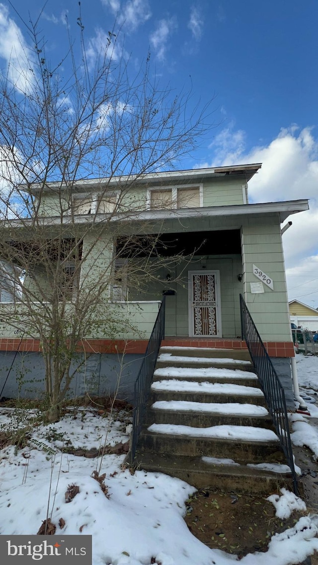 snow covered property entrance with a porch