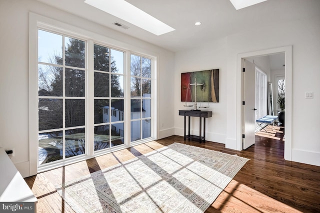 interior space featuring wood-type flooring, plenty of natural light, and a skylight