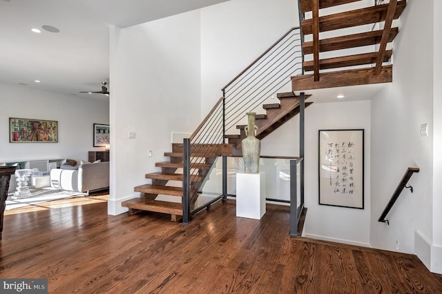 staircase featuring ceiling fan and hardwood / wood-style floors