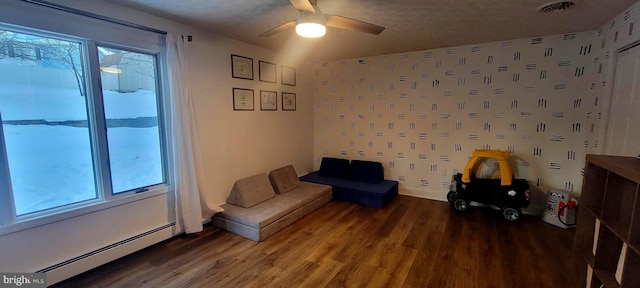 sitting room with hardwood / wood-style flooring, a baseboard radiator, ceiling fan, and a wealth of natural light