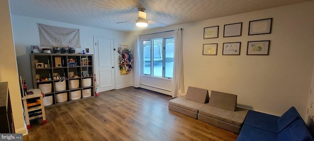 interior space with hardwood / wood-style flooring, a baseboard radiator, ceiling fan, and a textured ceiling