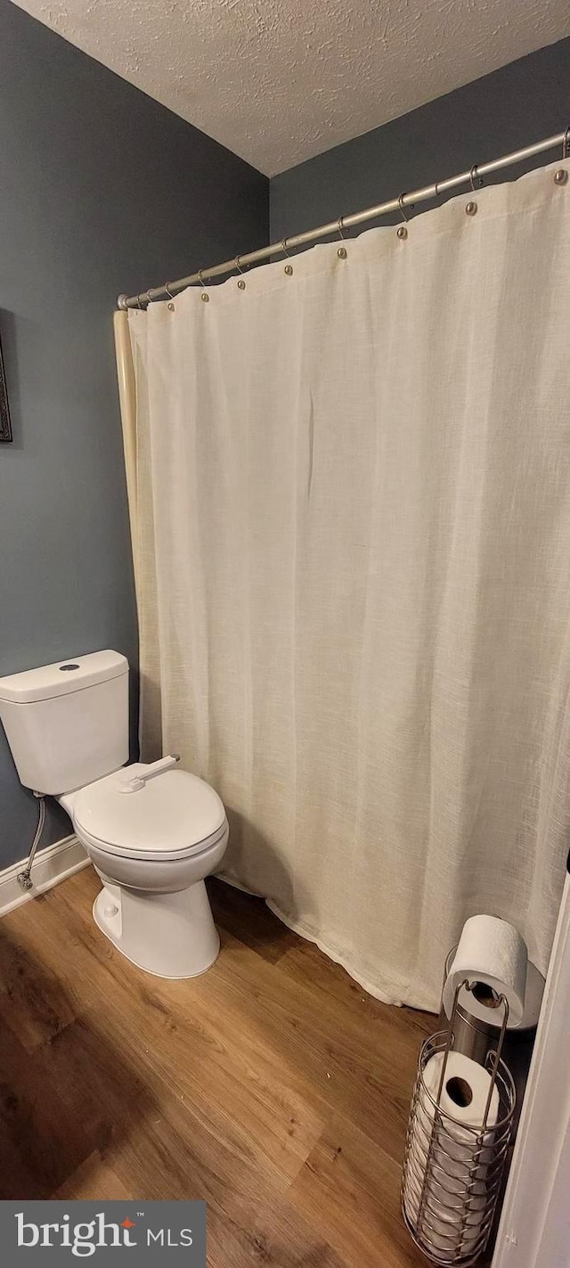 bathroom featuring hardwood / wood-style flooring, toilet, and a textured ceiling