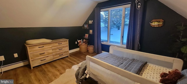 bedroom with a baseboard radiator, dark hardwood / wood-style floors, and vaulted ceiling