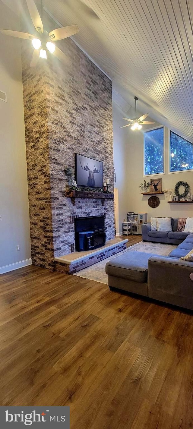 unfurnished living room with ceiling fan, a large fireplace, high vaulted ceiling, and hardwood / wood-style floors