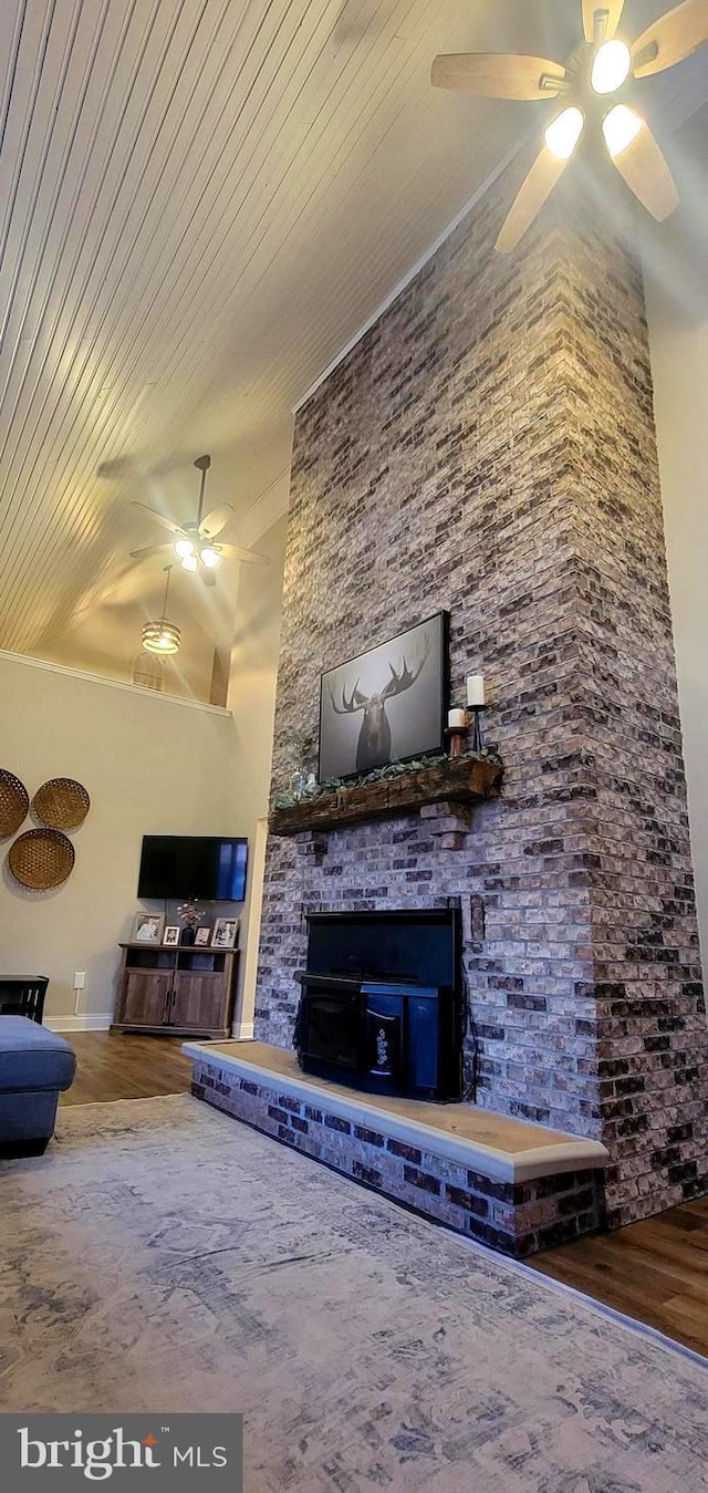 unfurnished living room with hardwood / wood-style floors, a stone fireplace, and ceiling fan