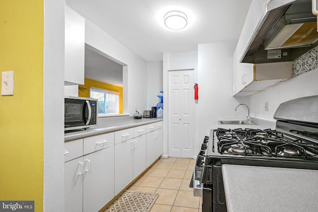 kitchen featuring sink, light tile patterned floors, black gas stove, custom range hood, and white cabinets