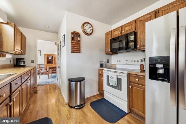 kitchen featuring white range with electric cooktop, stainless steel fridge with ice dispenser, and light wood-type flooring