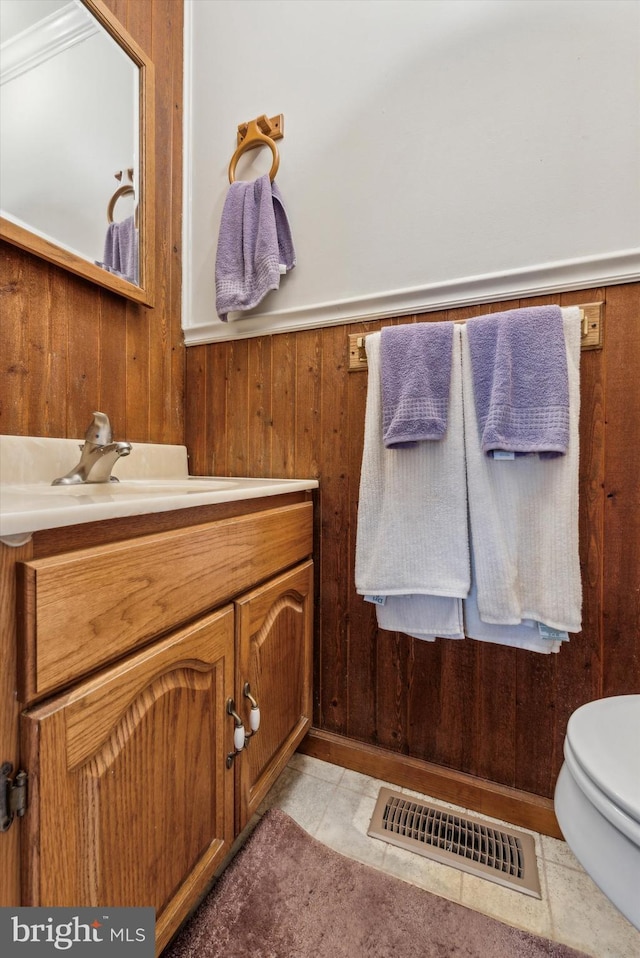 bathroom featuring vanity, toilet, and wood walls