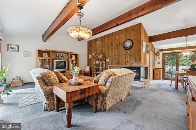 living room with wooden walls, a chandelier, lofted ceiling with beams, and carpet