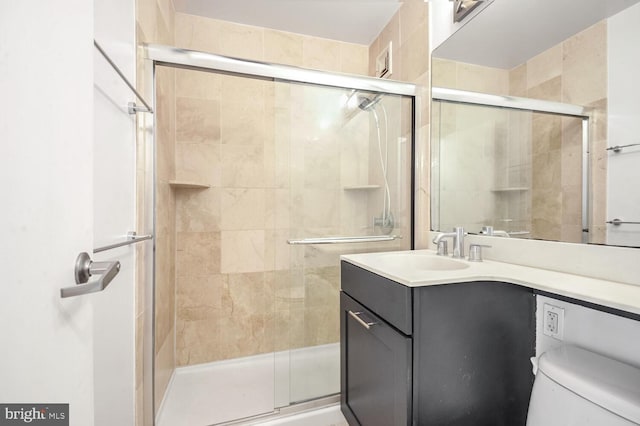 bathroom with an enclosed shower, vanity, and toilet