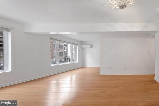 empty room with a wall mounted air conditioner and light hardwood / wood-style floors