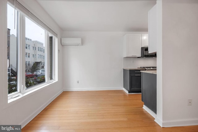 kitchen with plenty of natural light, a wall mounted AC, decorative backsplash, and white cabinets