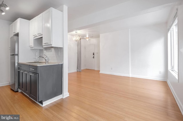 kitchen featuring white cabinetry, backsplash, stainless steel fridge, and light hardwood / wood-style flooring