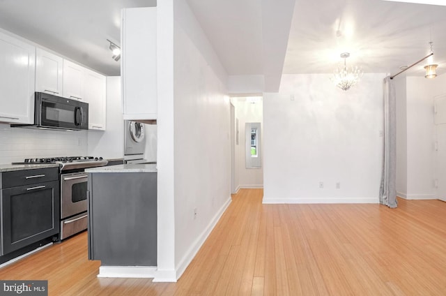 kitchen with decorative light fixtures, tasteful backsplash, white cabinetry, stainless steel gas stove, and light hardwood / wood-style flooring