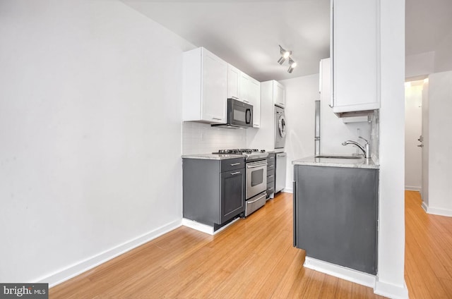 kitchen featuring sink, white cabinetry, stainless steel appliances, tasteful backsplash, and light wood-type flooring