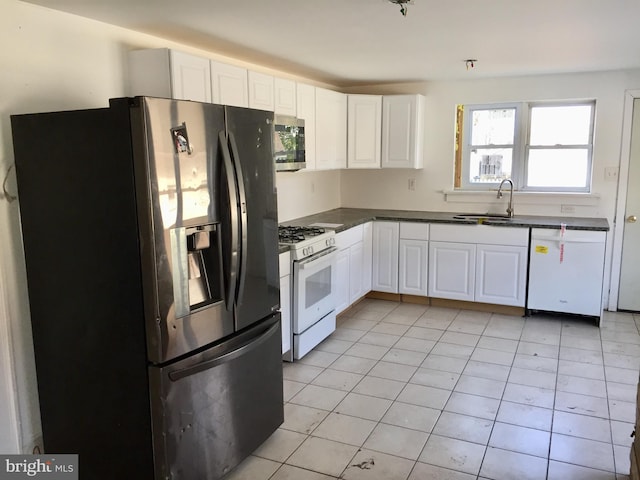 kitchen with appliances with stainless steel finishes, sink, light tile patterned floors, and white cabinets