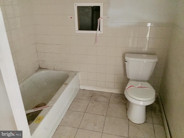 bathroom with tile walls, a washtub, tile patterned floors, and toilet