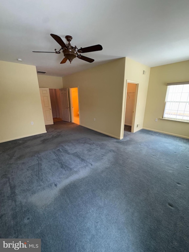 empty room with ceiling fan and dark carpet