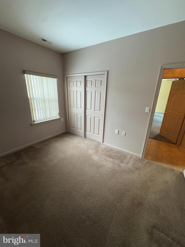 unfurnished bedroom featuring light carpet and a closet