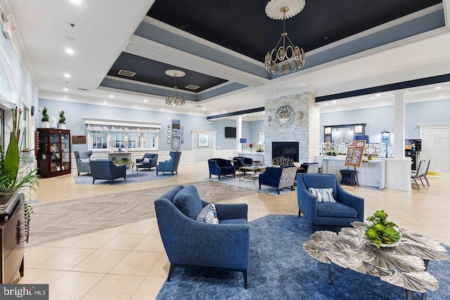 living room featuring ornamental molding, a tray ceiling, light parquet flooring, a fireplace, and decorative columns