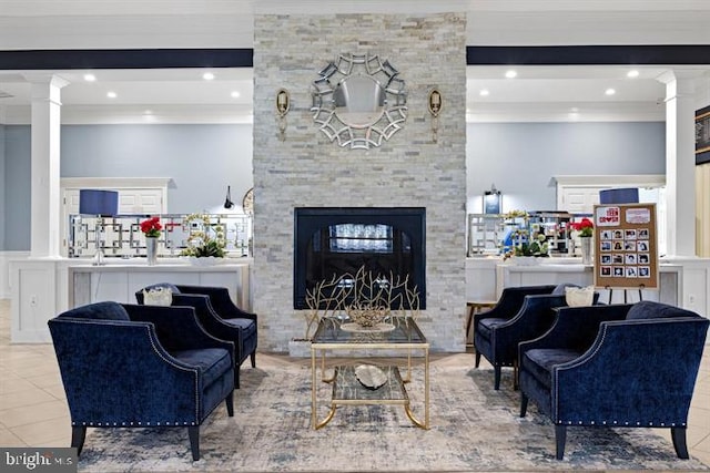 living room with tile patterned flooring, crown molding, a stone fireplace, and ornate columns