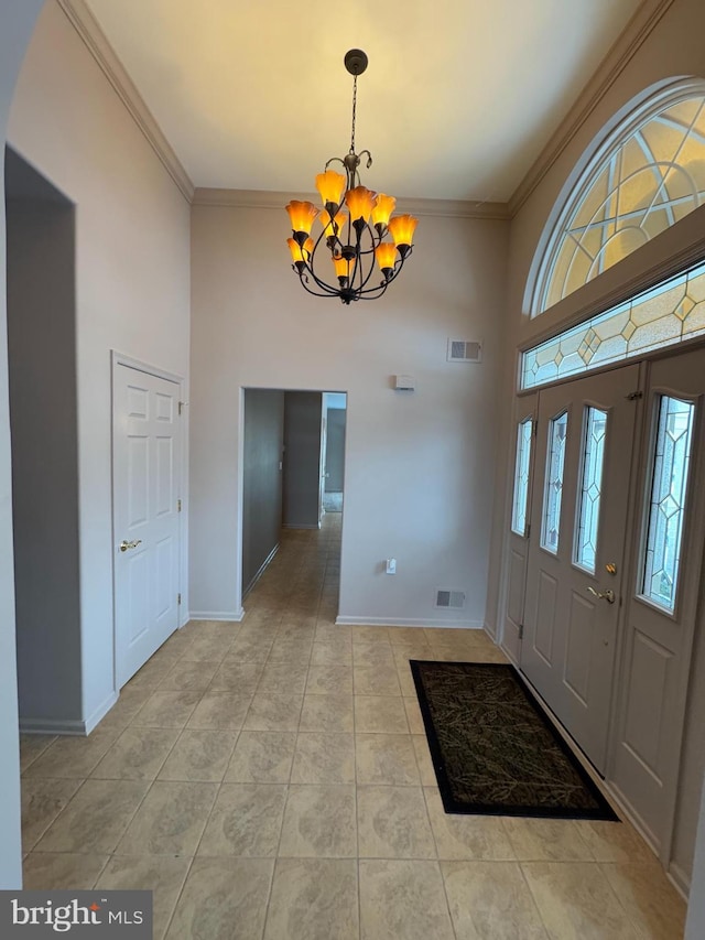 tiled foyer featuring a notable chandelier and crown molding