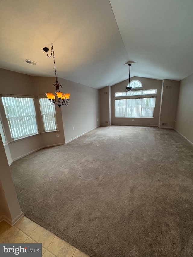 unfurnished living room with light carpet, ceiling fan with notable chandelier, a wealth of natural light, and vaulted ceiling