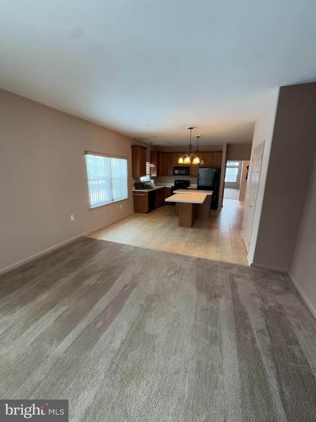 interior space with pendant lighting, a breakfast bar, black appliances, a kitchen island, and light colored carpet