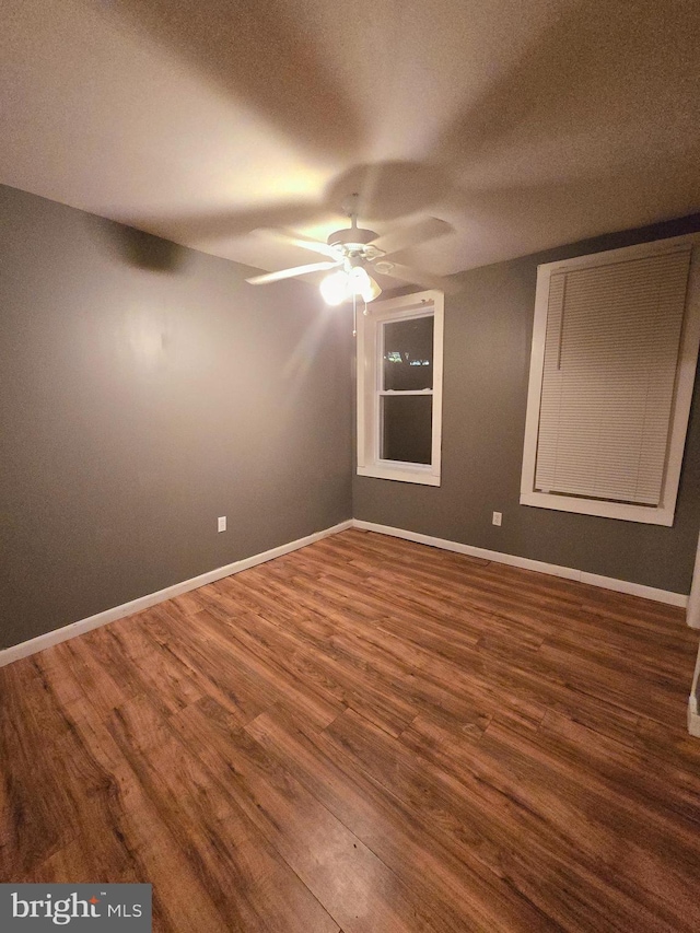 empty room with dark hardwood / wood-style flooring and ceiling fan