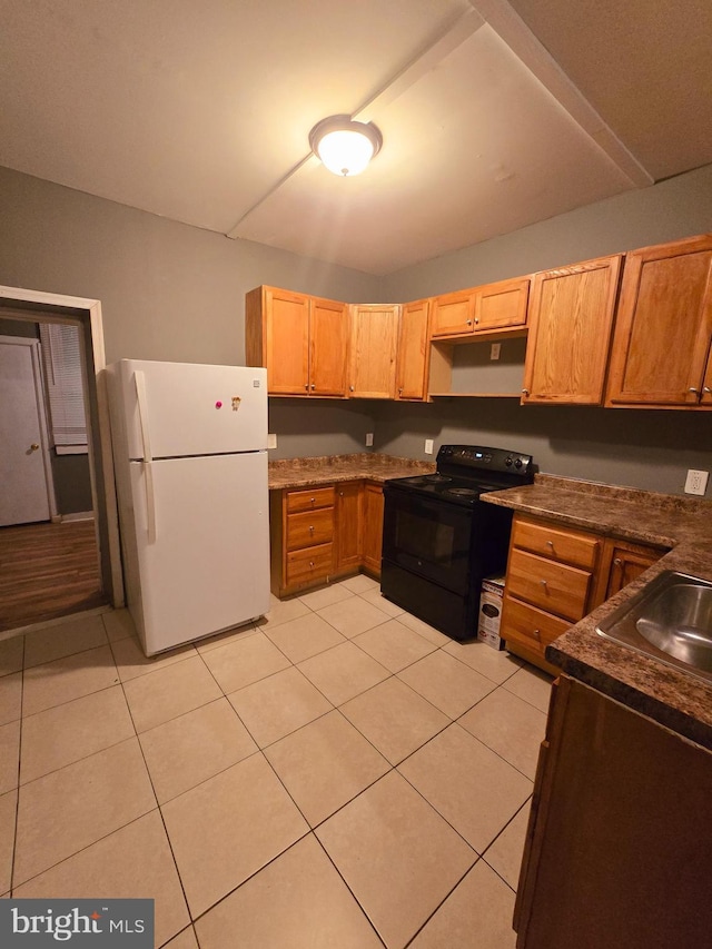 kitchen featuring light tile patterned floors, sink, white refrigerator, built in desk, and black range with electric cooktop