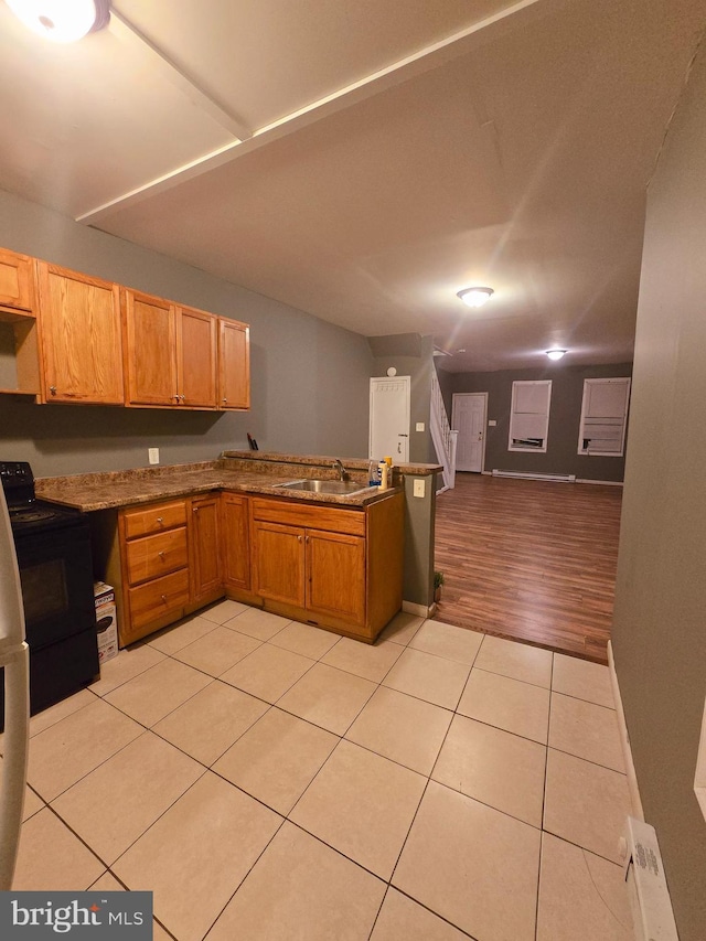 kitchen featuring black / electric stove, a baseboard heating unit, sink, and light tile patterned floors