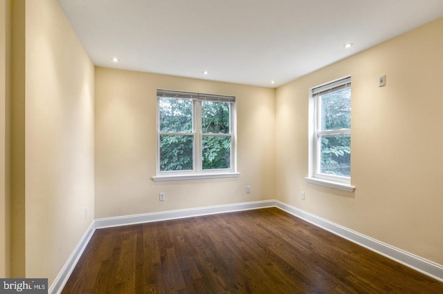 empty room featuring plenty of natural light and dark hardwood / wood-style floors